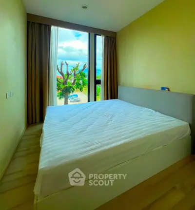 Cozy bedroom with large window and scenic view, perfect for relaxation.