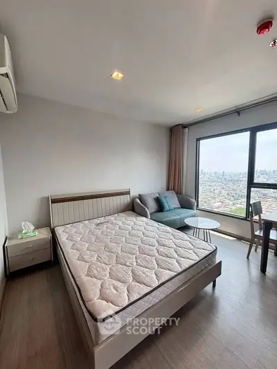 Modern bedroom with city view, featuring a cozy bed, sofa, and large window.