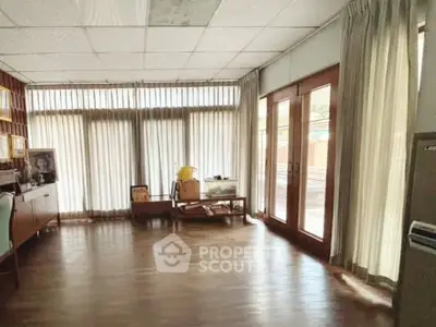 Spacious living room with wooden flooring and large windows offering natural light.