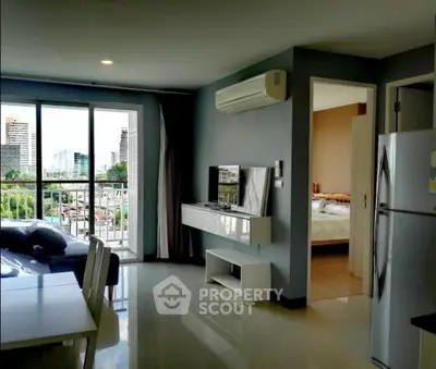 Modern apartment living room with balcony and city view, featuring sleek furniture and air conditioning.