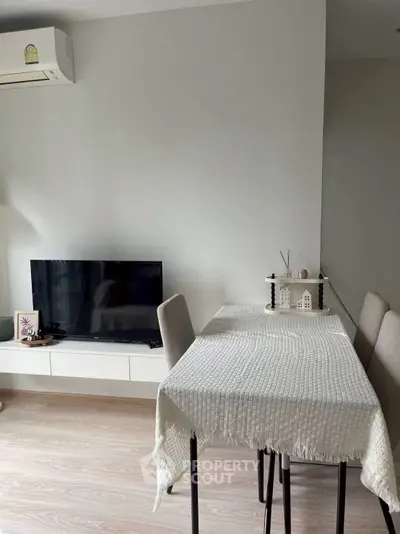 Modern dining area with sleek table, chairs, and wall-mounted TV in a cozy living space.