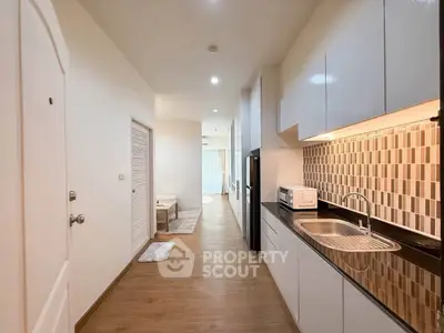 Modern kitchen with sleek cabinetry and stylish backsplash in a bright apartment hallway.