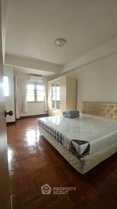 Cozy bedroom with wooden flooring and natural light, featuring a comfortable bed and wardrobe.