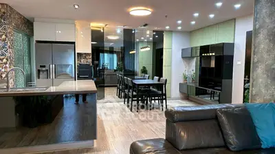 Modern open-plan living room with sleek kitchen and dining area, featuring stylish decor and ample natural light.