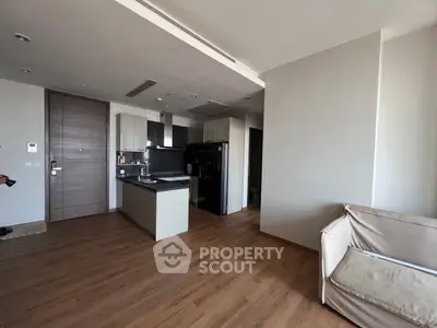 Modern open-layout living room with sleek kitchen and hardwood floors