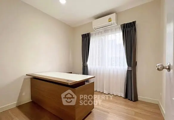 Bright study room with wooden desk and large window, perfect for productivity.