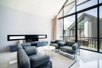 Modern living room with stylish furniture and large windows offering a stunning view of contemporary architecture.