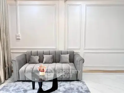Elegant living room with plush gray sofa and modern glass coffee table on a soft rug.