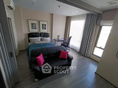 Modern bedroom with stylish decor and natural light, featuring a cozy seating area and workspace.