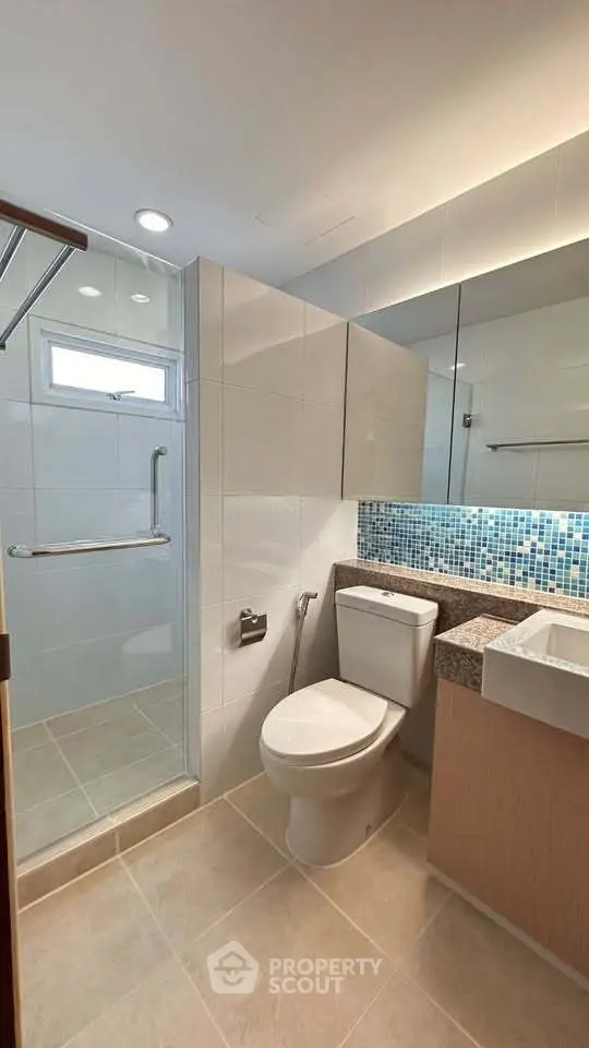 Modern bathroom with sleek design, featuring a glass shower and stylish mosaic backsplash.