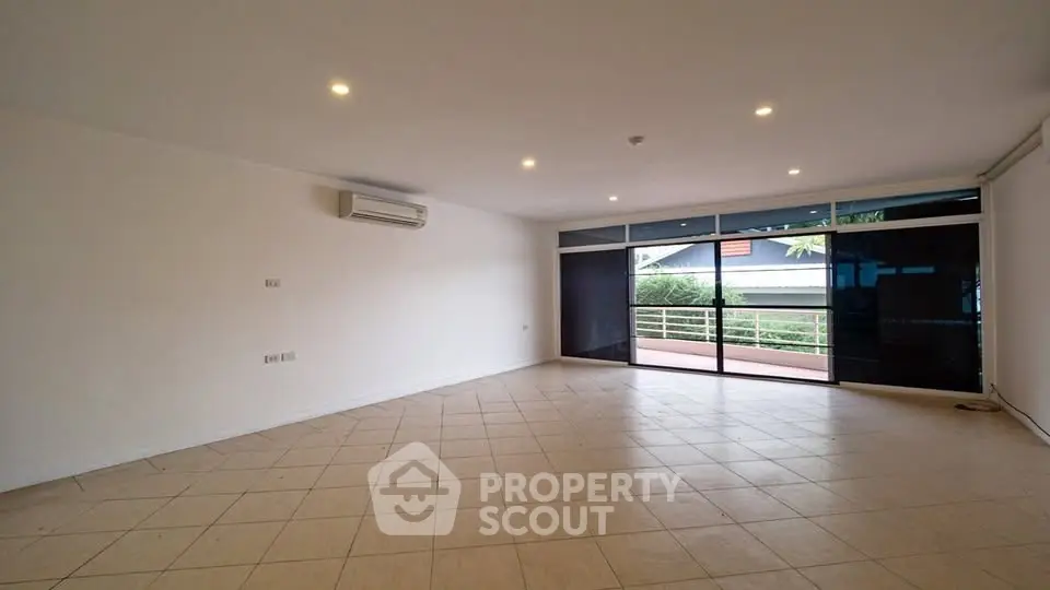 Spacious empty living room with large windows and tiled floor