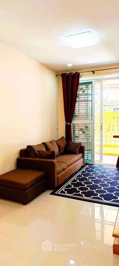 Cozy living room with brown sofa and modern decor, featuring large window for natural light.