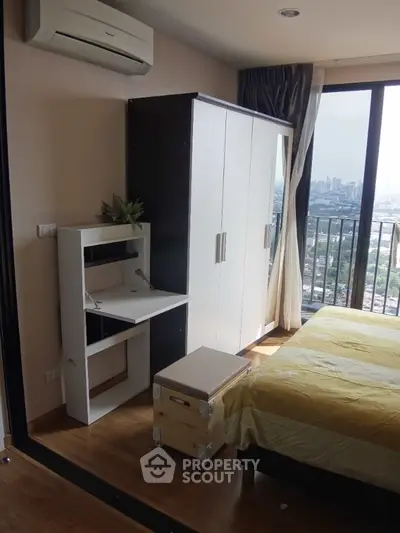 Modern bedroom with city view, featuring a sleek wardrobe and compact desk, perfect for urban living.