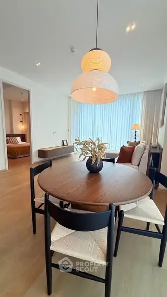 Modern dining area with stylish wooden table and chairs, adjacent to cozy living room and bedroom.