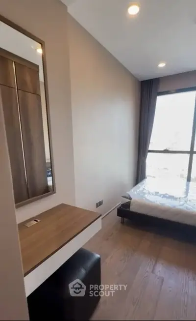 Modern bedroom with wooden flooring, large window, and built-in wardrobe.
