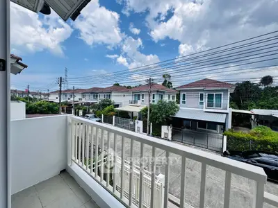 Charming suburban view from a cozy balcony overlooking modern homes under a clear blue sky.