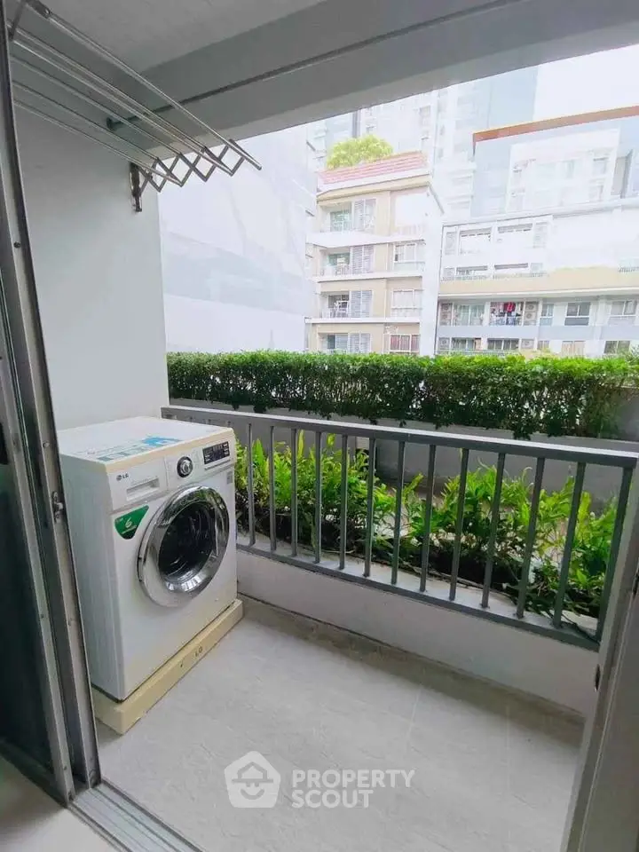 Charming balcony with washing machine and lush greenery view in modern apartment.