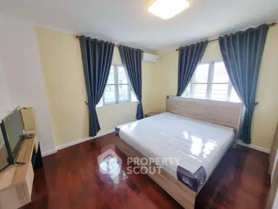 Spacious bedroom with hardwood floors and large windows for natural light.