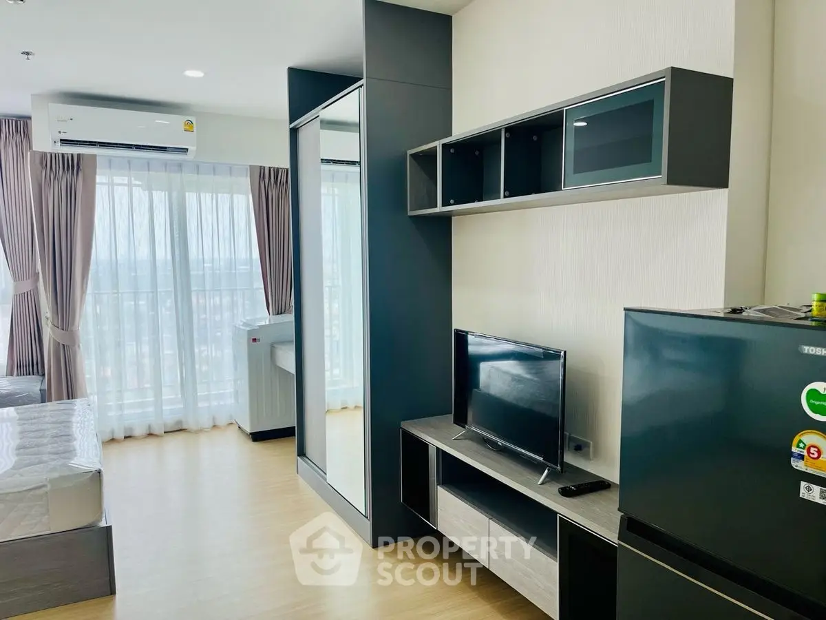 Modern studio apartment with sleek furniture and large windows offering natural light.