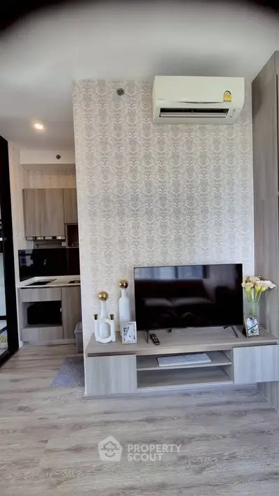 Modern living room with stylish decor and built-in kitchen appliances, featuring a sleek TV setup and air conditioning.