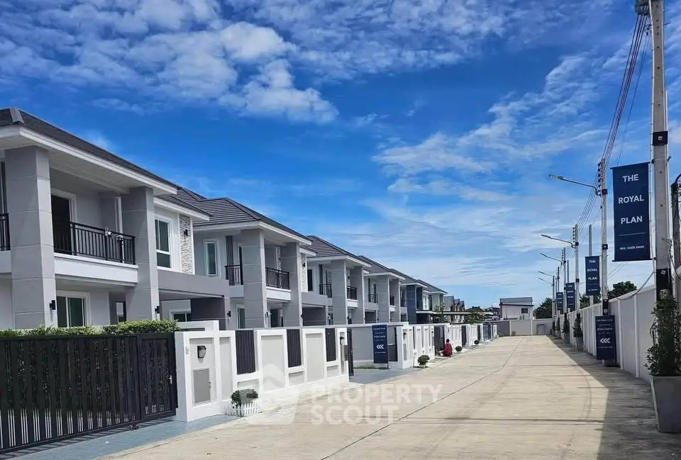 Luxurious modern townhouses with private balconies in a serene neighborhood under a clear blue sky.