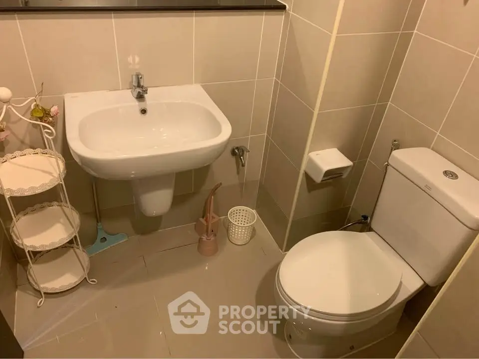 Modern bathroom with sleek fixtures and neutral tiles, featuring a pedestal sink and toilet.