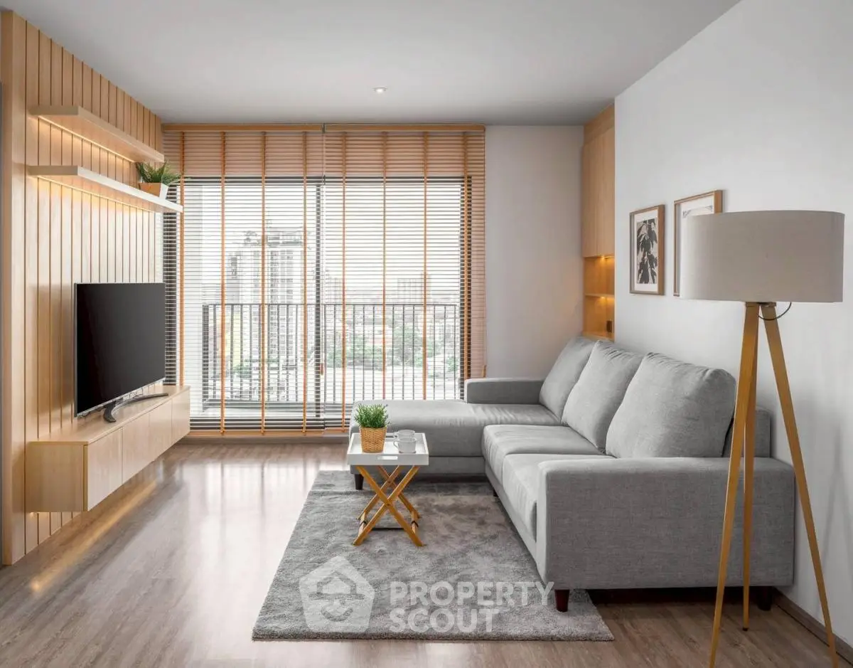 Modern living room with stylish decor and large window offering city view.