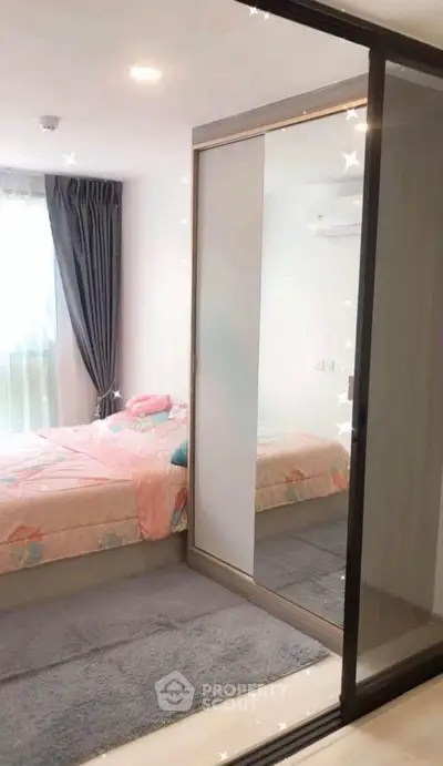 Cozy bedroom with sliding mirrored closet and soft pink bedding, perfect for a serene retreat.
