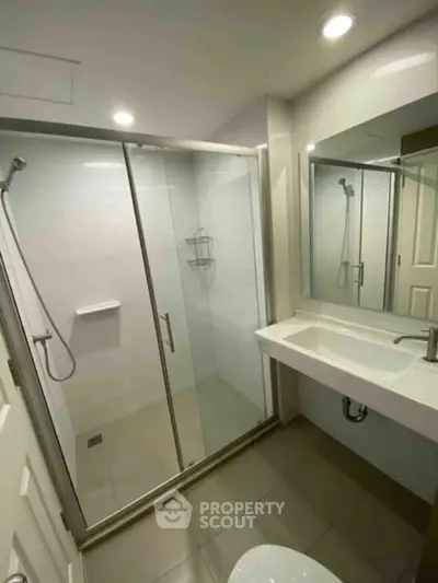Modern bathroom with glass shower enclosure and sleek vanity in a contemporary home.