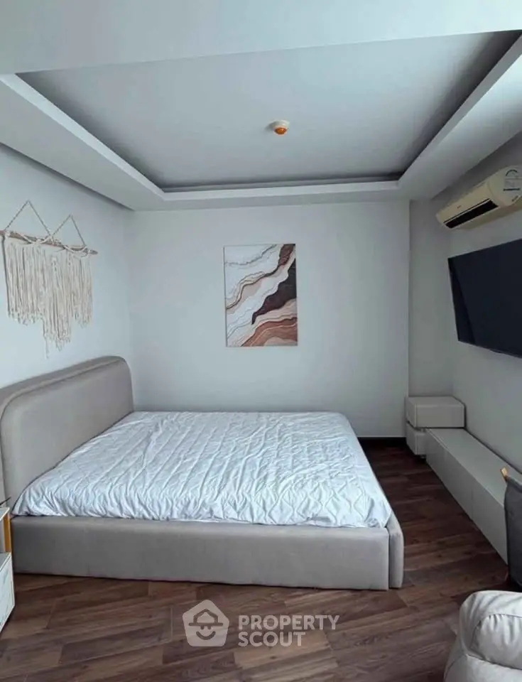 Modern bedroom with stylish decor and wall-mounted TV in a cozy apartment.