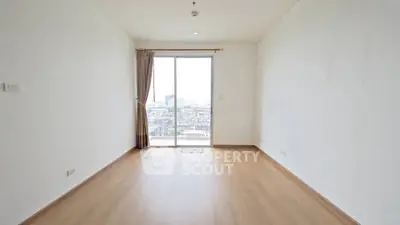 Spacious empty room with wooden flooring and city view from large window.