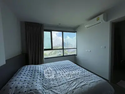Spacious bedroom with large window offering stunning city views, featuring modern air conditioning and cozy bedding.