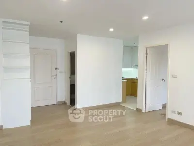 Spacious modern apartment interior with wooden flooring and open kitchen layout.