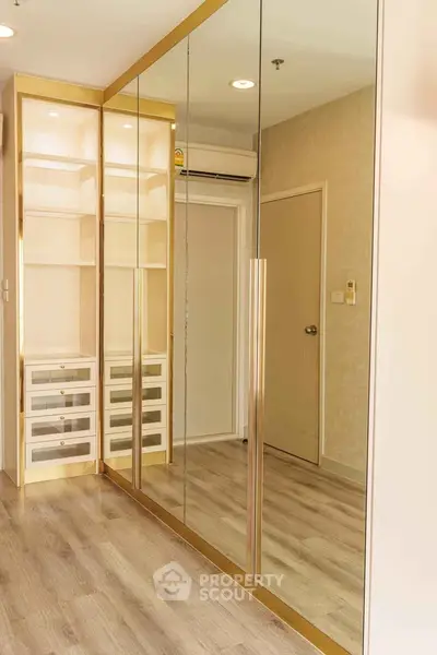 Modern bedroom with mirrored wardrobe and wooden flooring