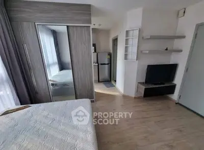 Modern studio apartment with sleek design, featuring a cozy bed, mirrored wardrobe, and compact kitchen area.