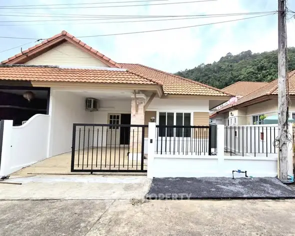 Charming single-story house with tiled roof and gated driveway in a serene neighborhood.
