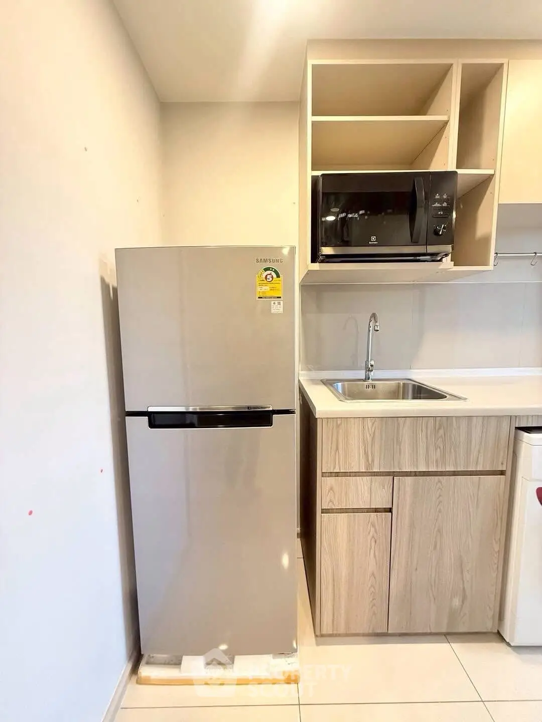 Modern kitchen with sleek fridge and microwave, featuring a stylish sink and cabinetry.