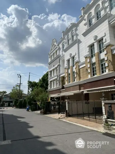 Elegant multi-story residential building with classic architecture and sunny street view.