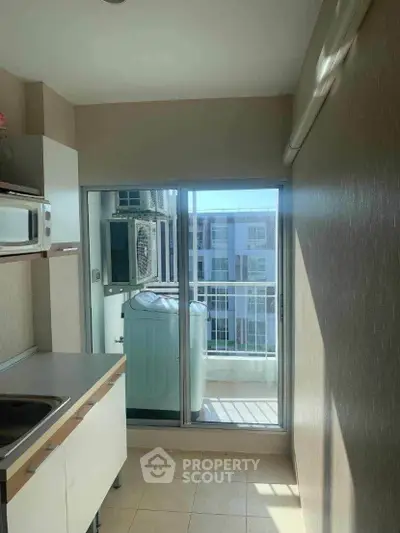 Compact kitchen with balcony view and washing machine in modern apartment