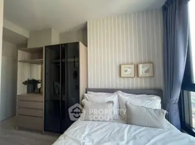 Modern bedroom with stylish decor and large window offering natural light.