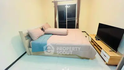 Cozy bedroom with modern decor and large TV, perfect for relaxation.