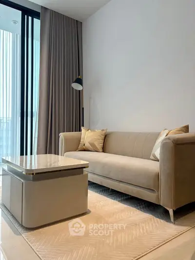 Modern living room with elegant beige sofa and stylish coffee table near large window with curtains.