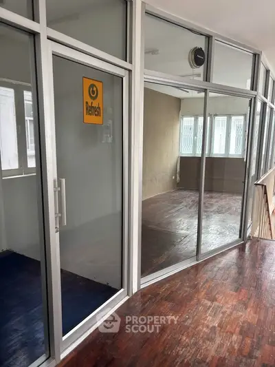 Spacious office space with glass partitions and wooden flooring, ideal for modern work environments.