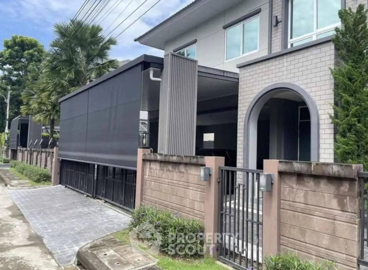 Modern two-story house with sleek design and gated entrance in a suburban neighborhood.