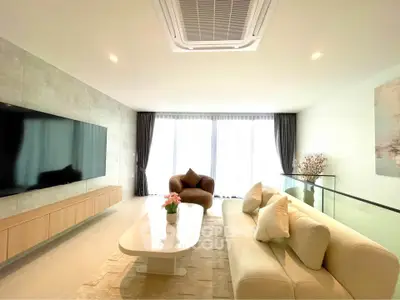 Modern living room with large TV and elegant furniture, featuring a cozy ambiance and natural light.