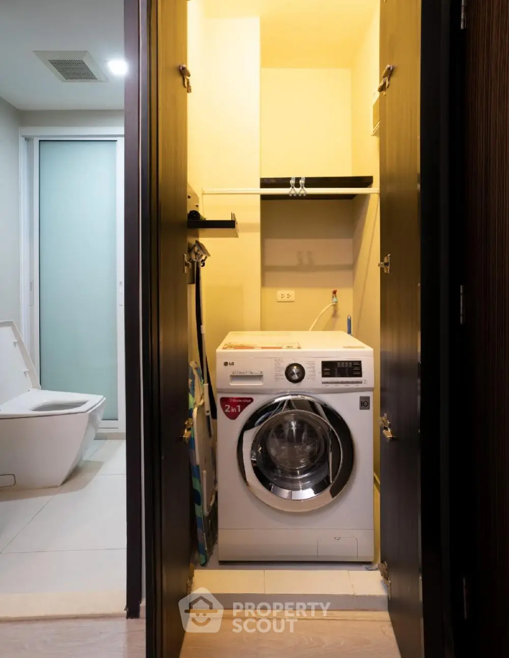 Compact laundry area with modern washing machine adjacent to bathroom in sleek apartment.