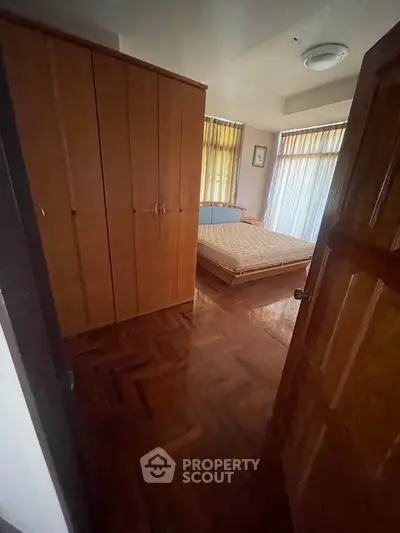 Cozy bedroom with wooden flooring and large wardrobe, perfect for a comfortable living space.