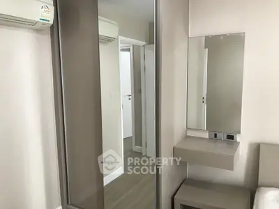 Modern bedroom with mirrored wardrobe and sleek vanity in stylish apartment.