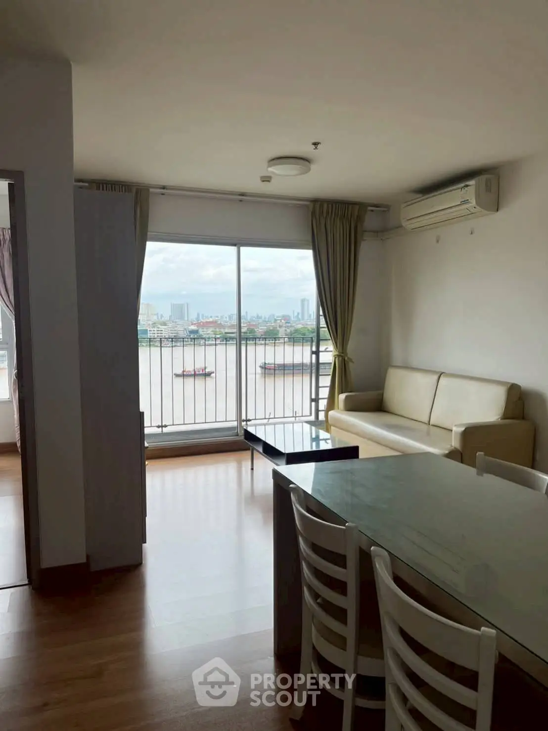 Spacious living room with river view and modern furnishings in a high-rise apartment.