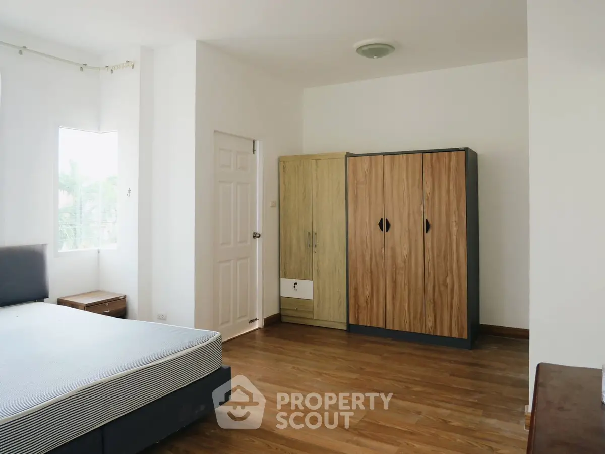 Spacious bedroom with wooden flooring and ample natural light